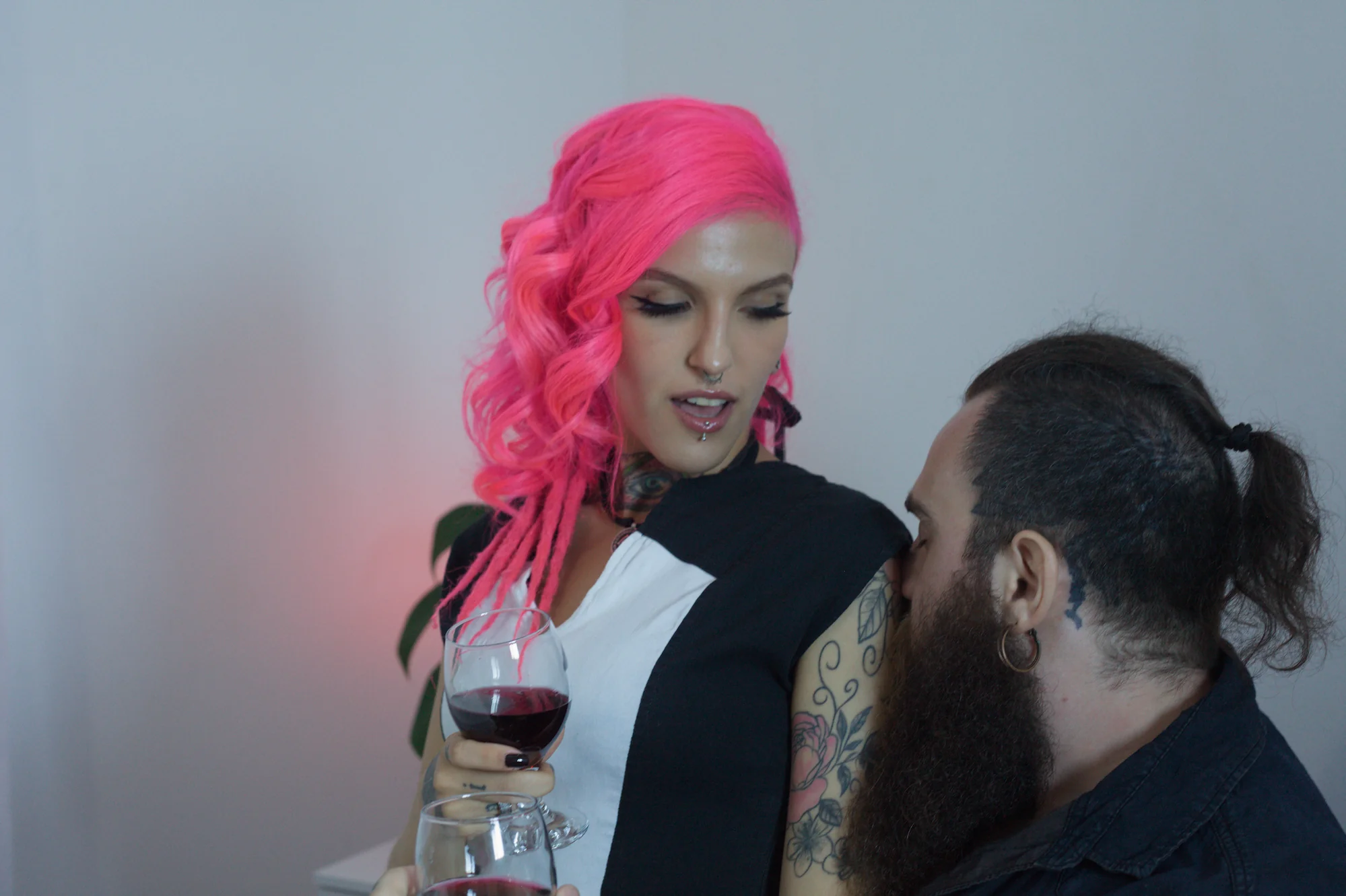 Qween de cabelo rosa e Bruno Iron com taças de vinho tinto — Quente Club